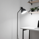 Modern lighting styles for home featuring a black floor lamp and minimalist desk setup.